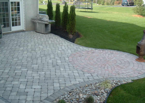 A brick patio with a grill and fire pit.