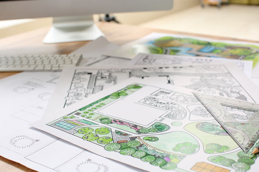 A desk with garden plans and a computer on it stock photo.
