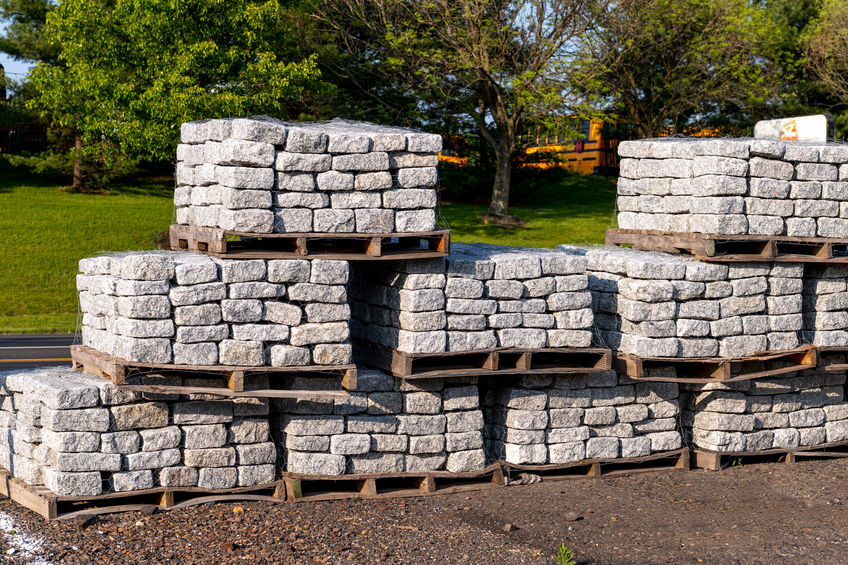 Stacked stone blocks on pallets in a yard stock photo.