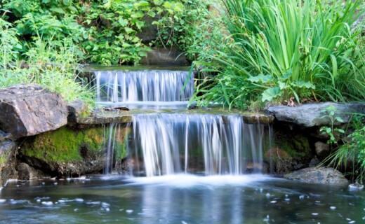 Fire Features & Water Features A pond with a waterfall in the middle of it.