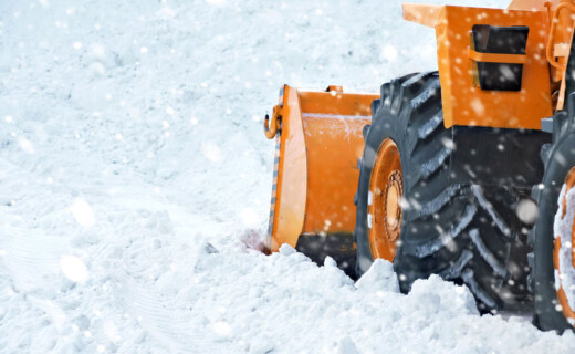 A snow plow is driving down a snowy road.