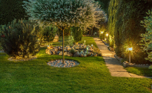 Landscape Lighting A garden at night with a pathway and trees.