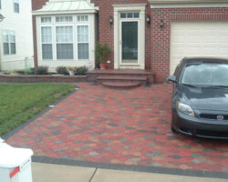 view of green front door on brick two story home with green lawn and brick driveway