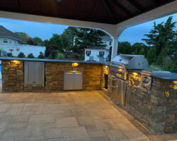 An outdoor kitchen with a fireplace and grill.