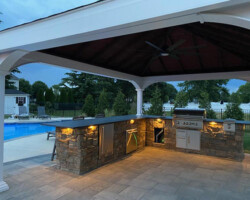 An outdoor kitchen with a fireplace and grill.