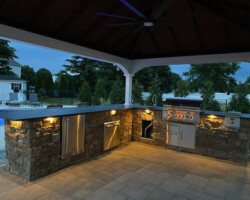 An outdoor kitchen with a fireplace and grill.