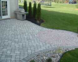 A brick patio with a grill and fire pit.